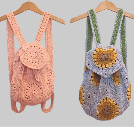 Wanderlust crochet backpacks in pink and sunflower blue, hanging on hangers