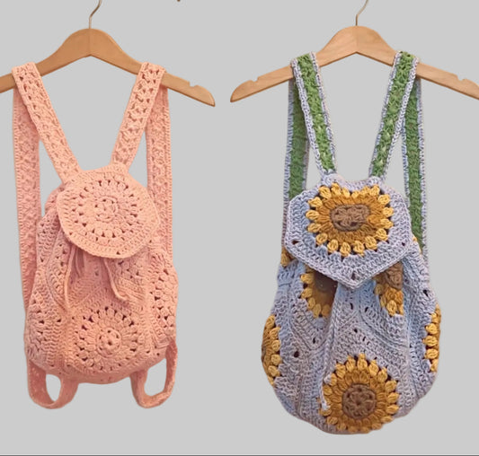 Wanderlust crochet backpacks in pink and sunflower blue, hanging on hangers